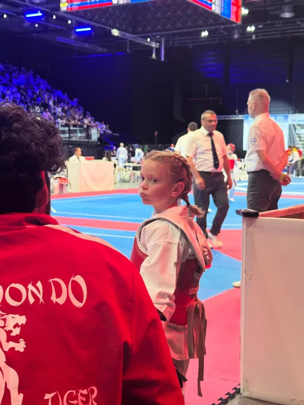 Eine junge Sportlerin steht mit einem Betreuer im roten Black-Tiger-Oberteil am Mattenrand.