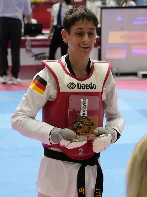 Ein junger Sportler zeigt stolz seine Medaille.