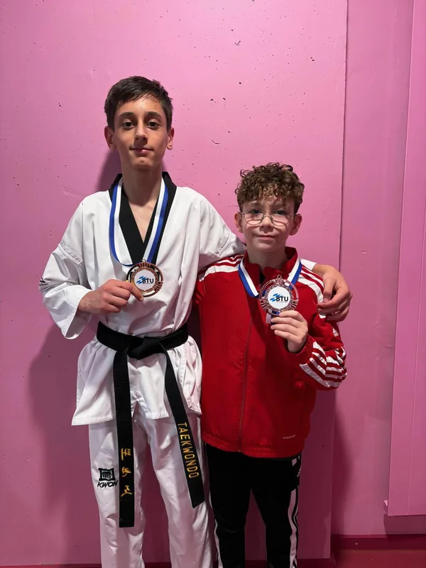 Zwei junge Sportler stehen mit ihren Medaillen für ein Foto zusammen.