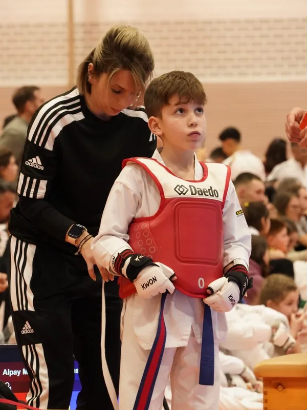 Eine Betreuerin hilft einem jungen Sportler mit seiner Schutzausrüstung.