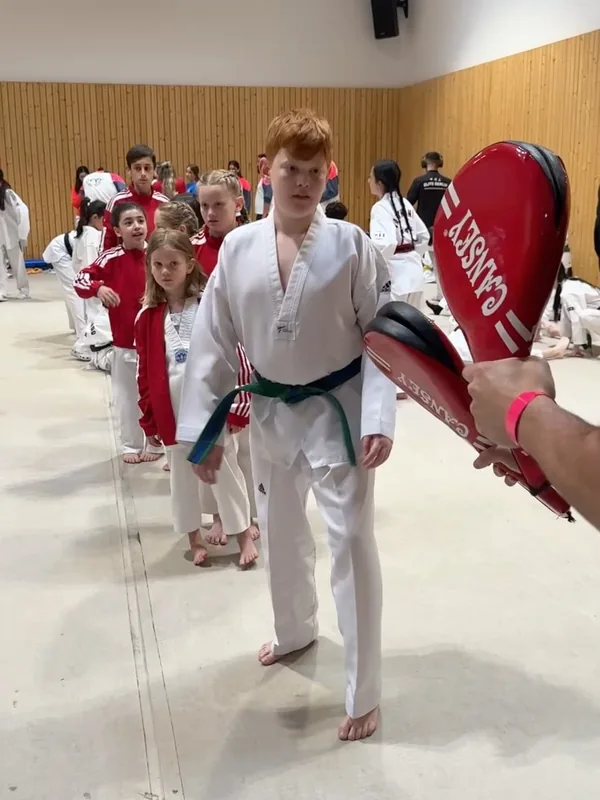 Kinder stehen beim Aufwärmen vor zwei roten Schlagpolstern nacheinander bereit.