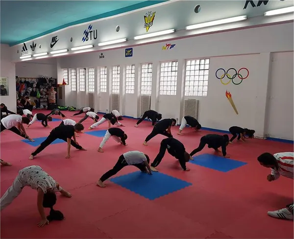 Kinder und Jugendliche wärmen sich gemeinsam in der Trainingshalle auf.