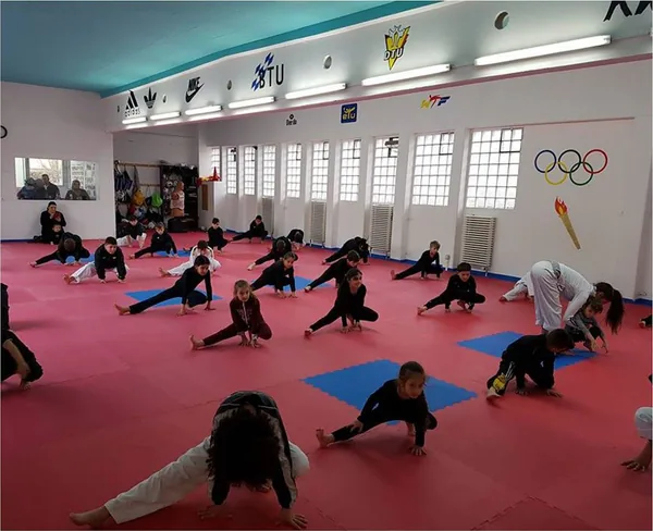 Kinder dehnen sich gemeinsam während des Taekwondo-Trainings.