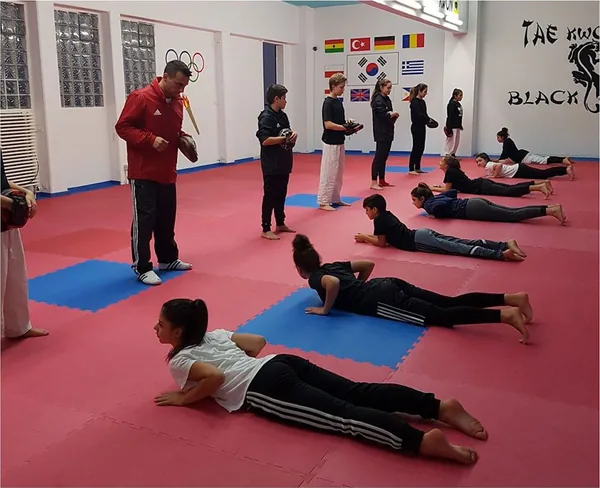 Ein Trainer begleitet Kinder und Jugendliche bei einer Kraftübung auf der Matte.